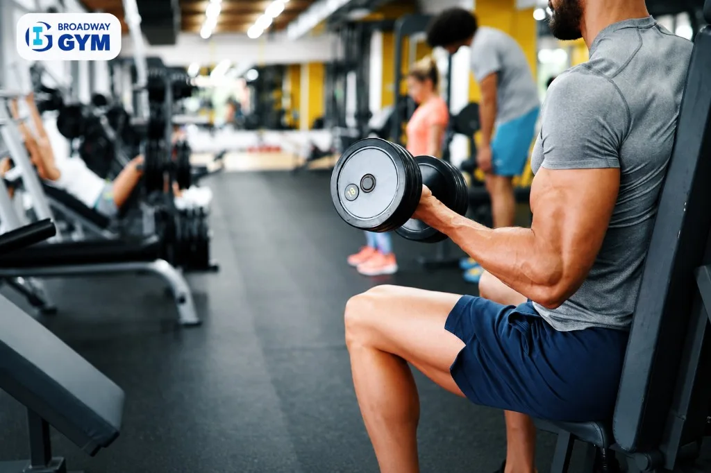Man performing a seated dumbbell curl at Broadway Gym